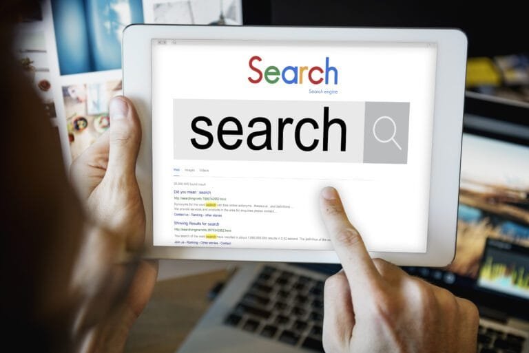 A person using a tablet to perform an online search, with the word 'search' displayed prominently on the screen.